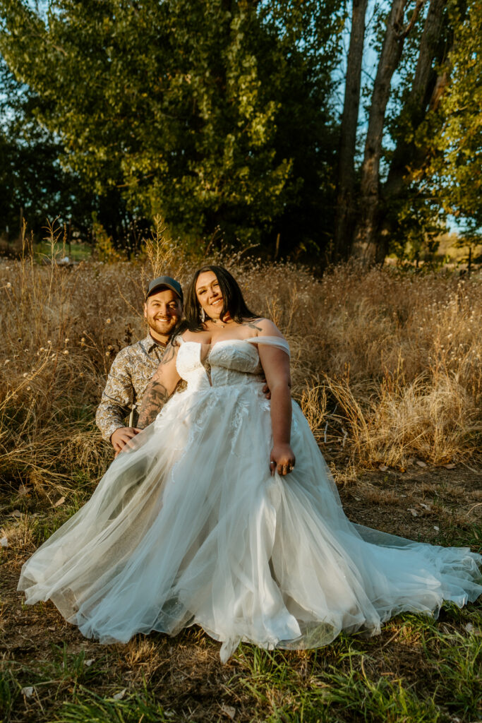 Bride and groom stand together in an intimate backyard wedding in Salon, NV, surrounded by lush greenery and soft, natural light. The couple gazes lovingly at each other, creating a warm and romantic atmosphere, with delicate floral arrangements adding elegance to the cozy outdoor setting.