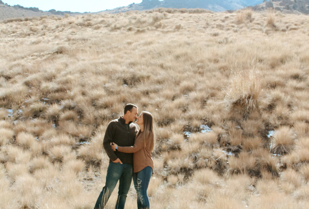 A joyful family photo captured by a Tucson wedding photographer: The couple smiles with their loved ones under the warm Arizona sunlight, surrounded by the stunning desert landscape featuring cacti and mountain views.