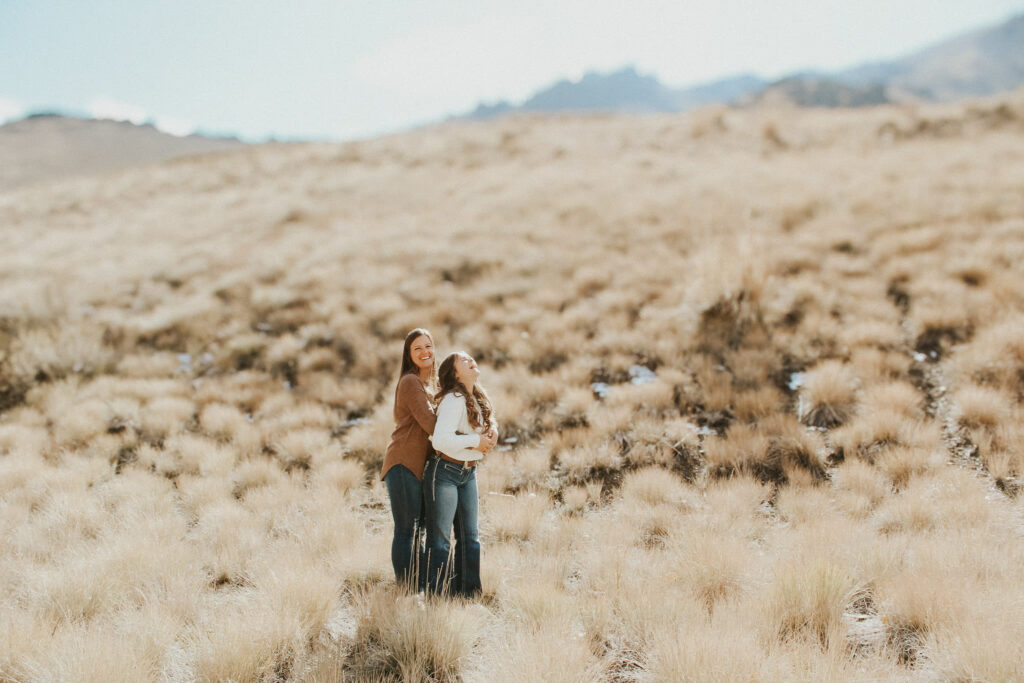  A tender moment captured by a Tucson wedding photographer: A mother and daughter share a warm embrace, smiling under the Arizona sun, with the desert's iconic cacti and golden hues in the background.