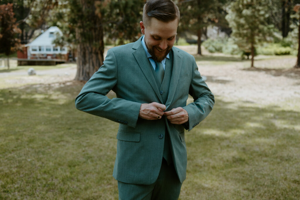 A groom adjusts his jacket, exuding confidence and style as he prepares for his wedding day. The tailored suit, complemented by a boutonniere, captures the sophistication of the moment, perfect for a timeless Tucson wedding.